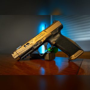 Canik TTI Combat 9mm pistol with TTI Bronze Cerakote slide, compensator, bronze aluminum magwell and spare magazine with +3 base pad, left side