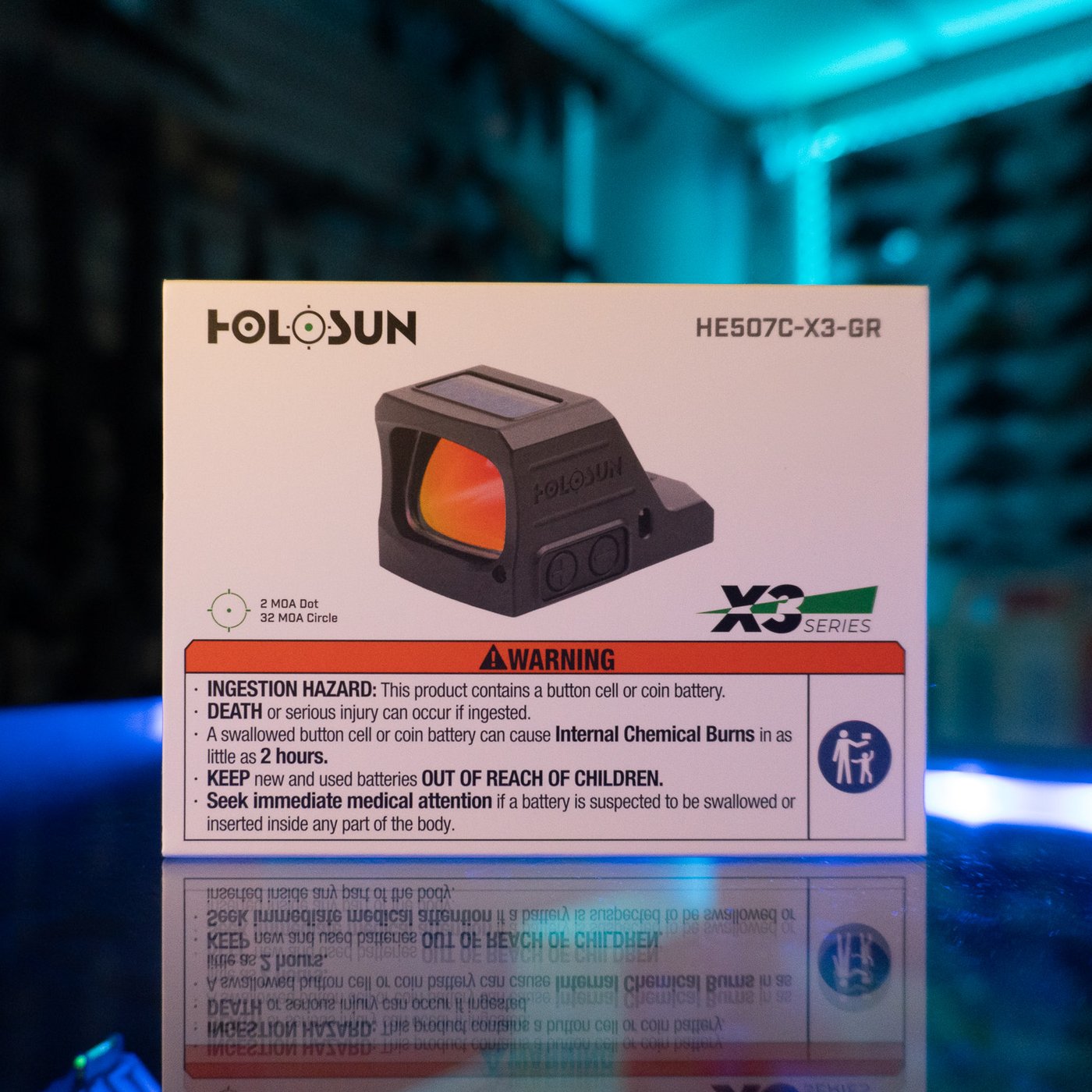 Holosun HE507C-X3-GR green multi-reticle open pistol sight in its retail box on a glass display counter