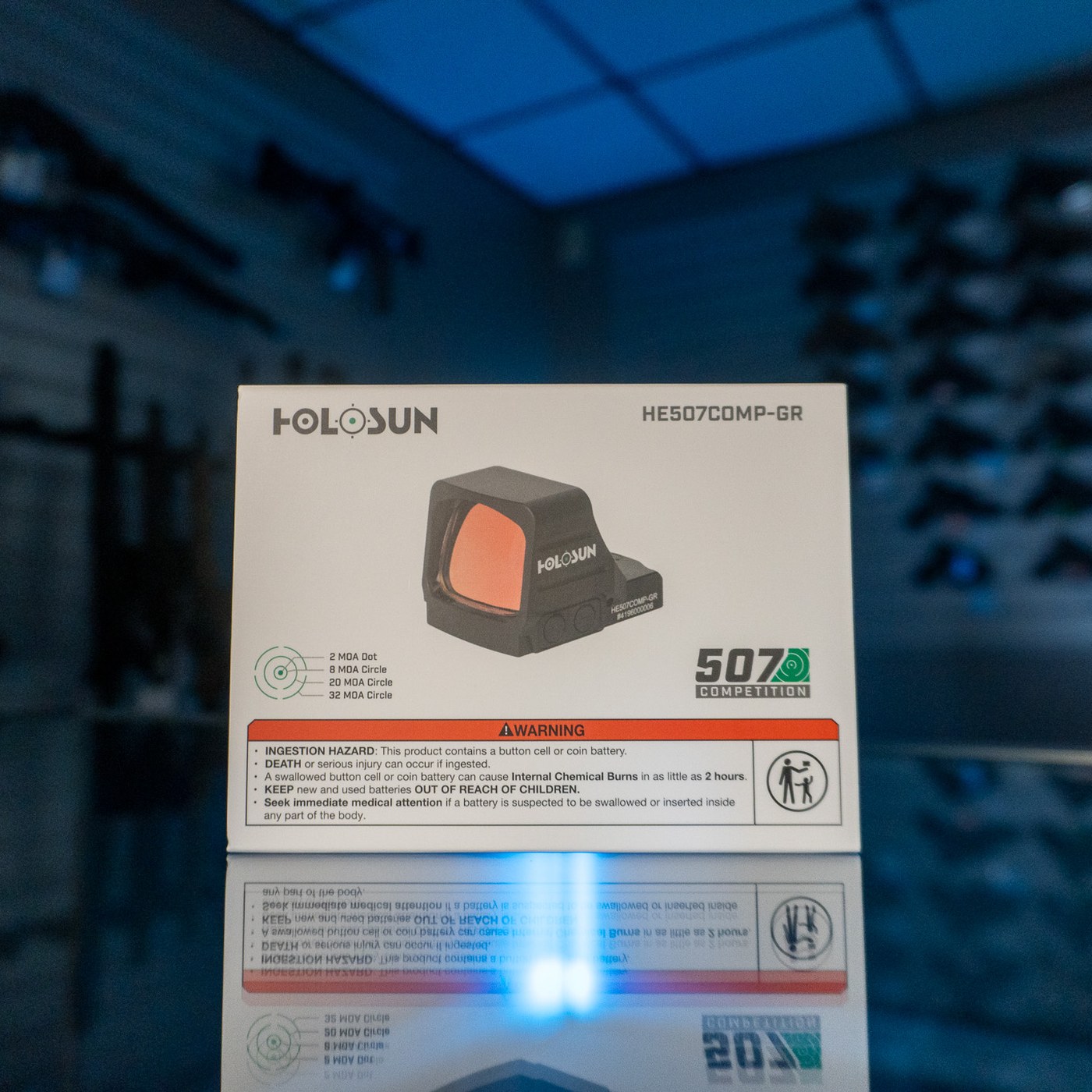 Holosun HE507COMP-GR green multi-reticle dot sight in its retail box on a glass display counter
