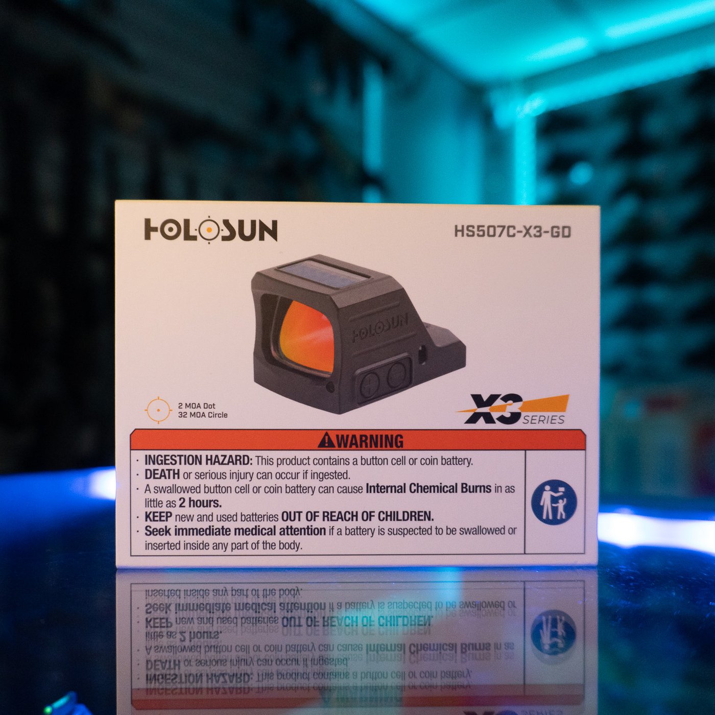 Holosun HS507C-X3-GD gold multi-reticle open pistol sight in its retail box on a glass display counter