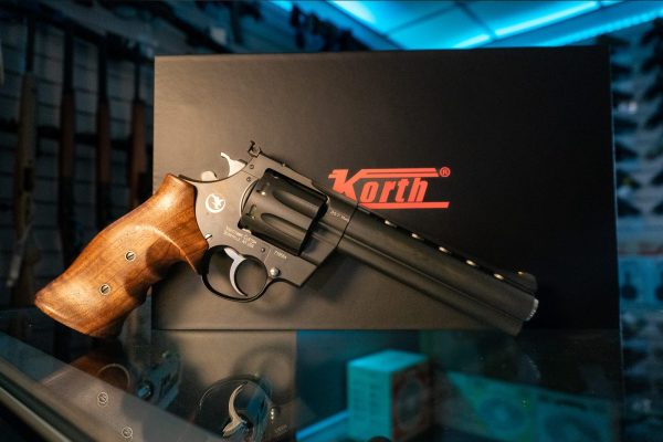 Korth Mongoose 8-Shot .357 Magnum revolver in black DLC, left side with Nighthawk Custom markings and walnut grip, in front of the Korth box