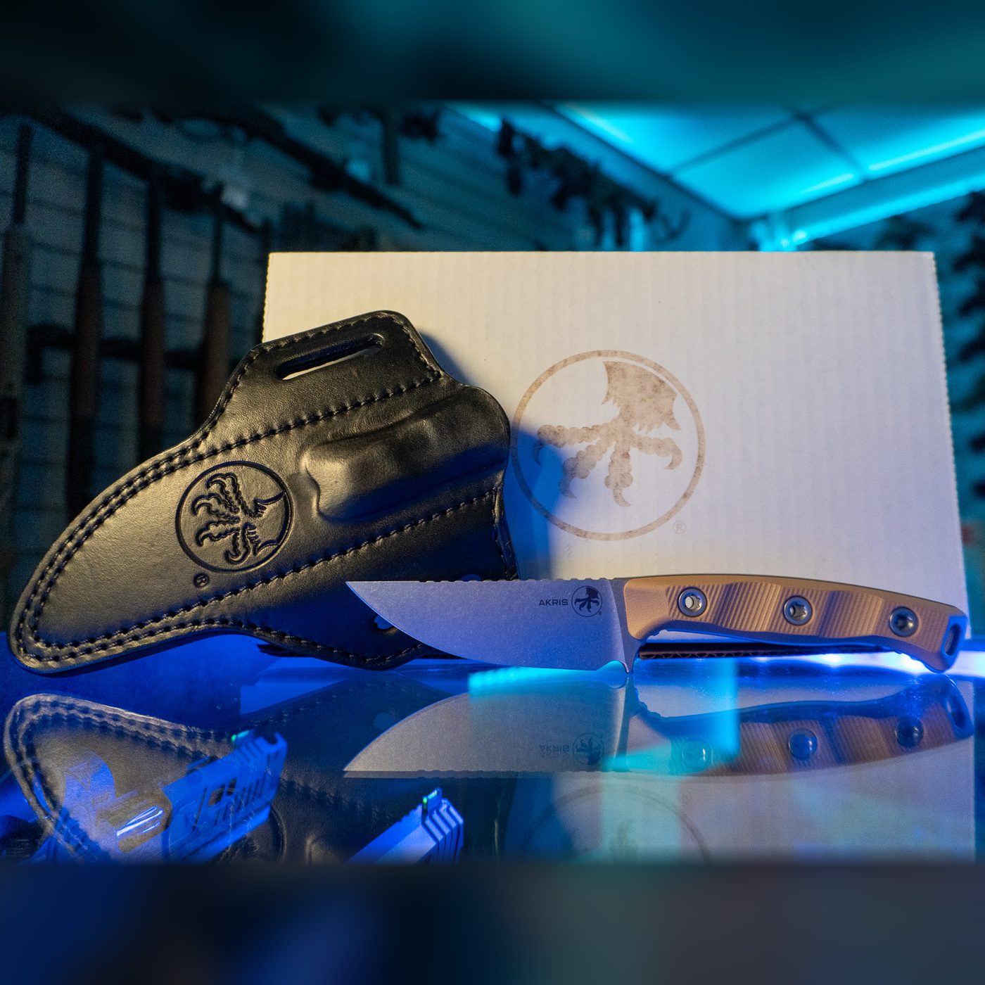 Microtech Akris fixed blade knife with stonewash drop point blade and Dark Earth G-10 handle, shown with its black leather sheath and Microtech box
