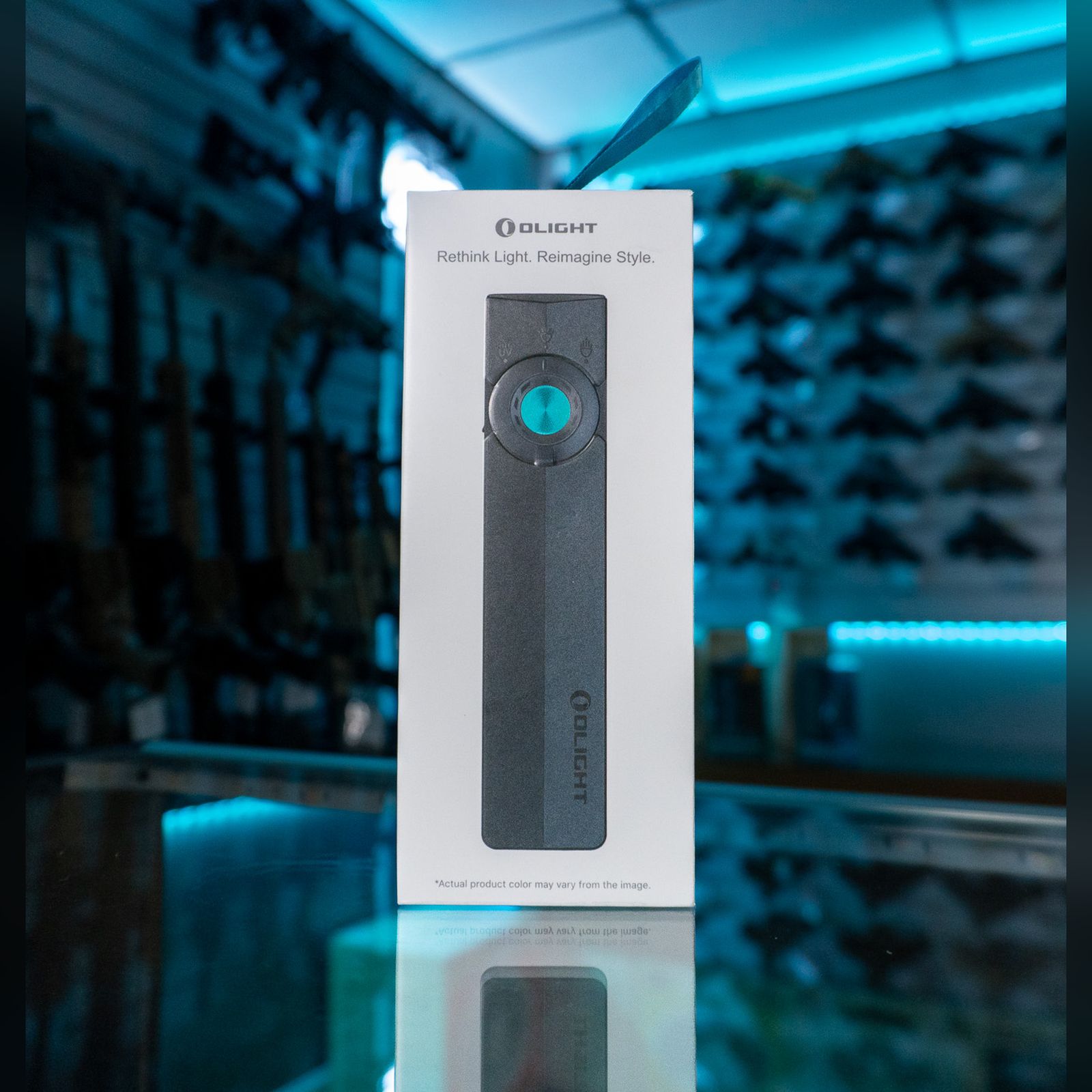 Olight ArkPro EDC flat flashlight in matte black in its retail box on a glass store counter
