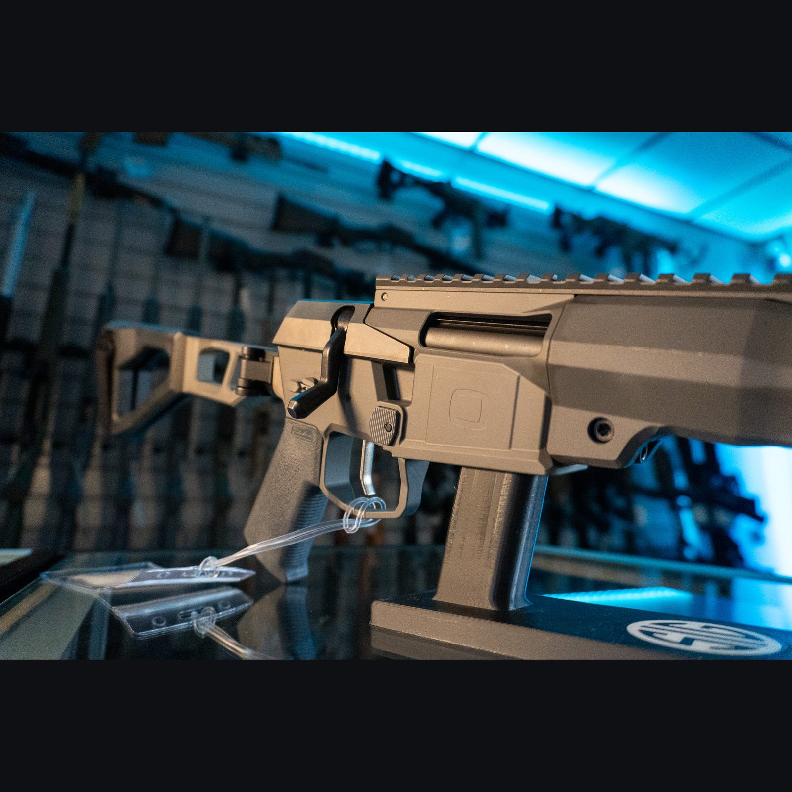 Close-up of the Q Mini Fix one-piece gray receiver with Q logo, bolt handle and Picatinny top rail