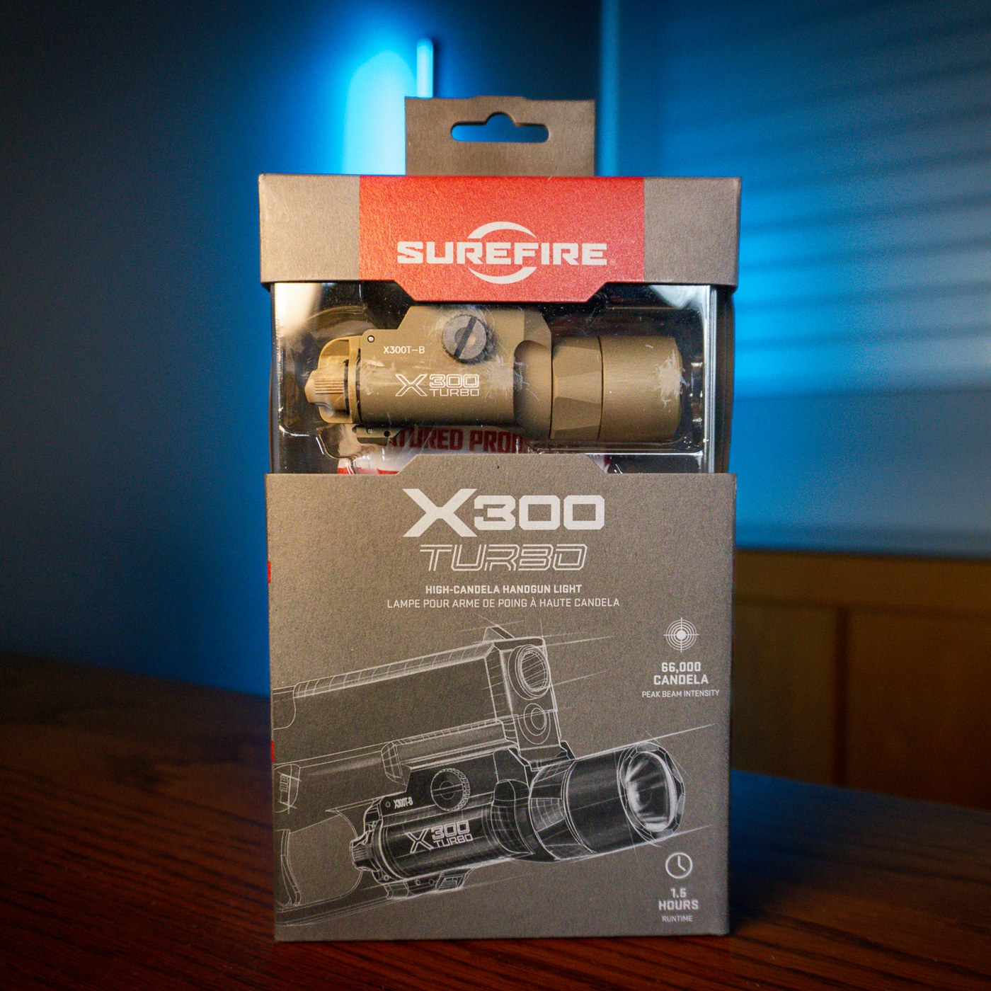 SureFire X300 Turbo handgun weapon light in tan inside its retail box on a wood table