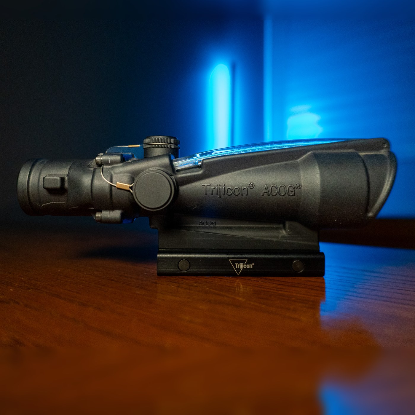 Trijicon ACOG 3.5x35 BAC riflescope with green horseshoe reticle and flattop mount, side view on a wood table